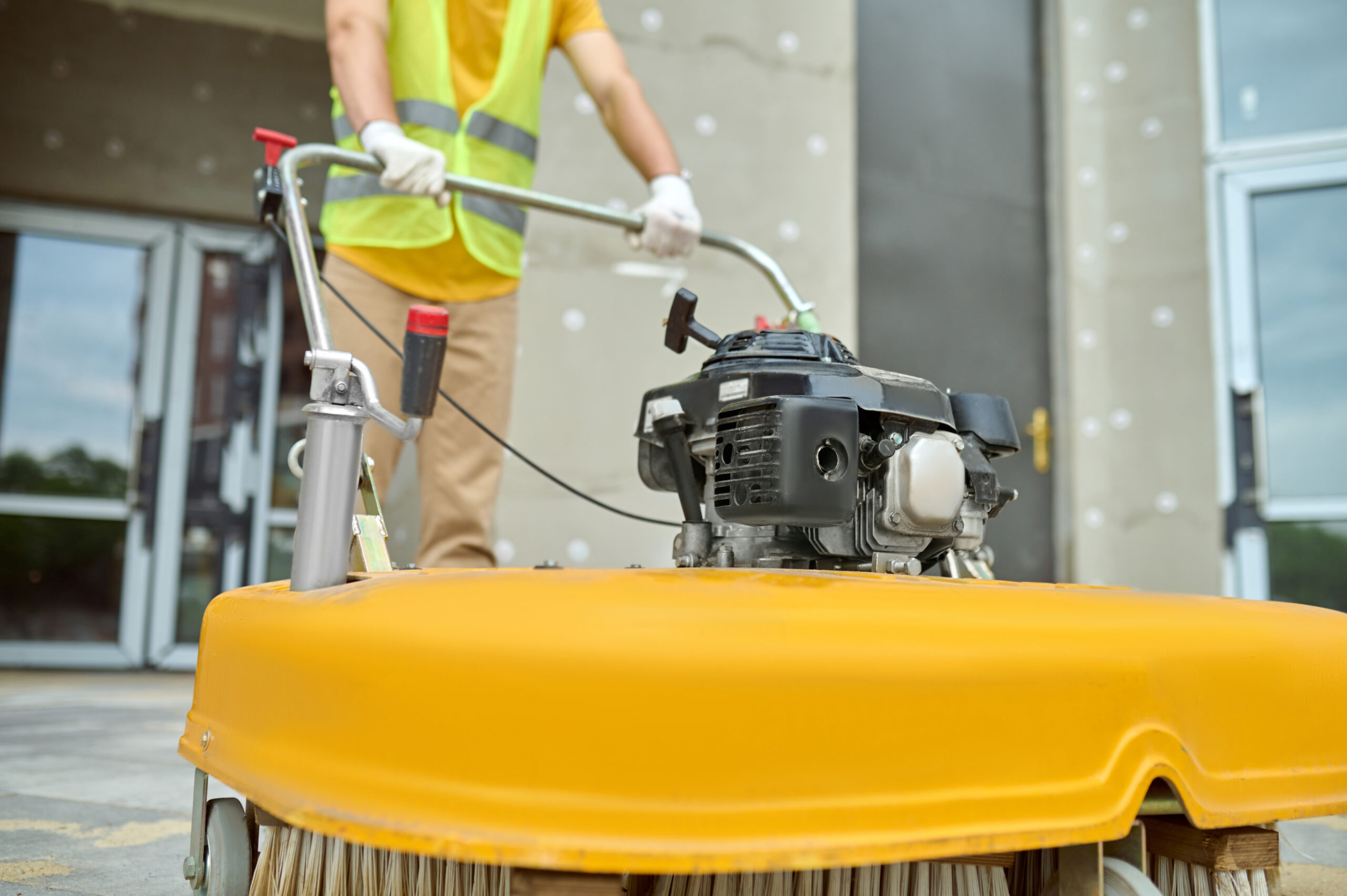 Cropped photo of a worker cleaning the outdoor floor tiles with a street sweeping machine